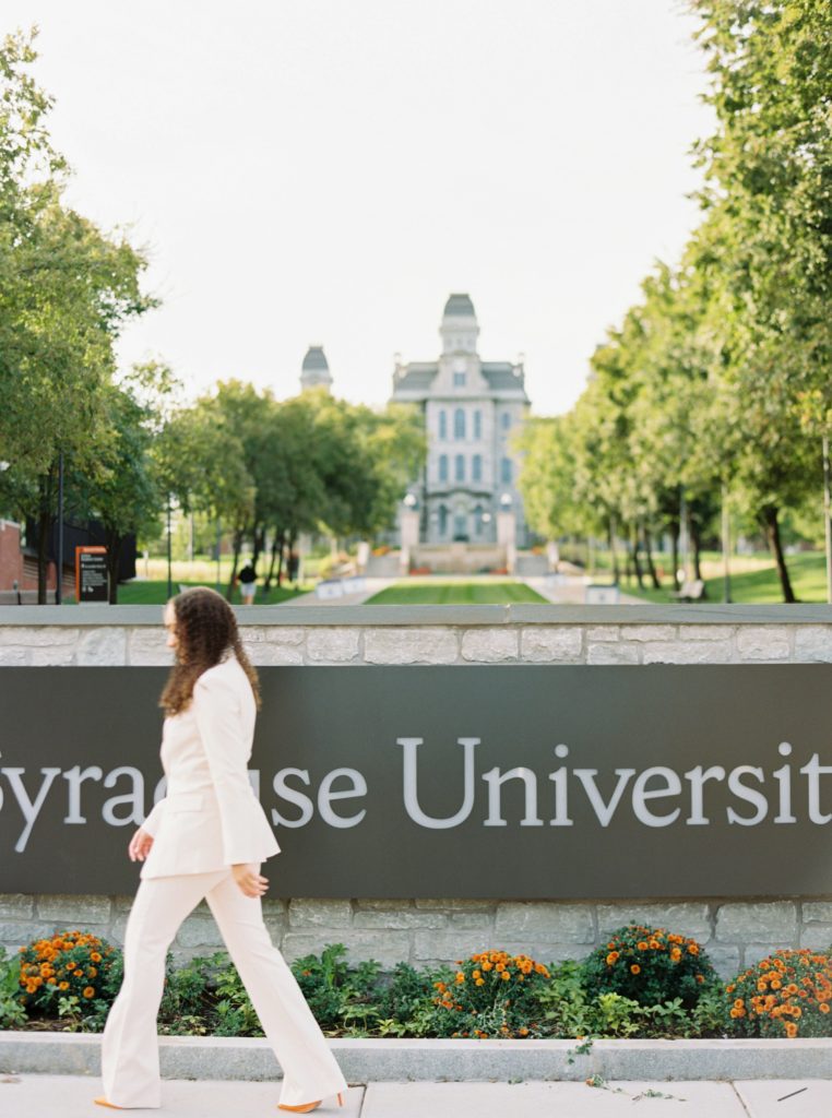 student walking by new Syracuse university sign, syracuse graduation session